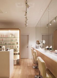 the interior of a hair salon with chairs and counter tops in front of mirrors on the wall