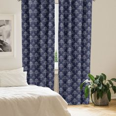 a bed room with a neatly made bed and two windows covered in blue curtain panels