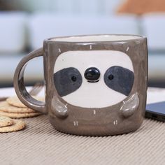 a coffee cup with a slot face on it next to crackers and a cell phone