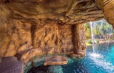 an outdoor swimming pool with waterfall in the middle and blue water running down it's sides