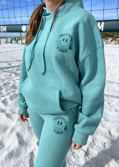 a woman standing in the snow wearing a blue sweatshirt and sweatpants