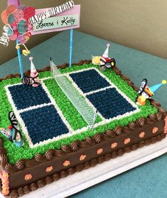 a birthday cake decorated with tennis courts and balloons