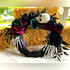 a wreath with skulls and flowers on it sitting in front of some hay bales