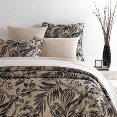 the comforter is made up with black and white floral designs on it, along with two decorative vases