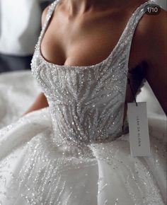 a woman in a wedding dress with a price tag on her neck and chest, sitting on a bed