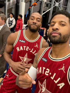 two basketball players standing next to each other in the middle of a room with people looking on