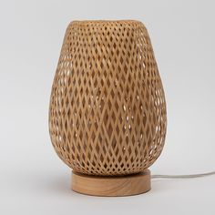 a wicker lamp with a wooden base on a white background, the light is turned on