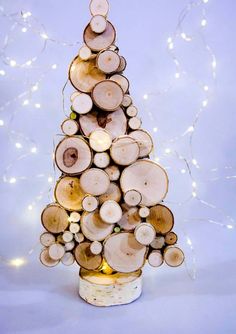 a christmas tree made out of logs with lights in the background on a white surface