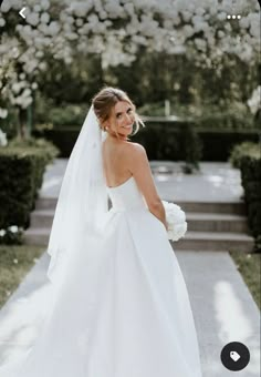 a woman in a wedding dress is standing outside