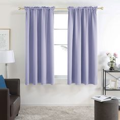 a living room filled with furniture and a window covered in purple drapes next to a chair