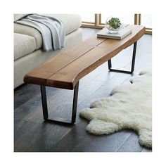 a wooden bench sitting on top of a floor next to a white sheepskin rug