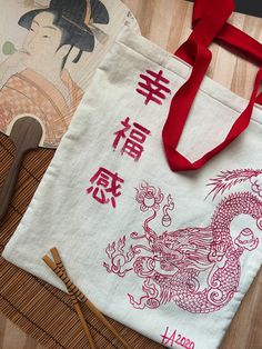 two bags with chinese writing on them sitting next to bamboo utensils and chopsticks