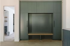 a wooden bench sitting in the middle of a room next to some cabinets and doors