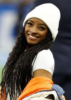 a woman with long dreadlocks smiles while holding a tennis racquet in her hand