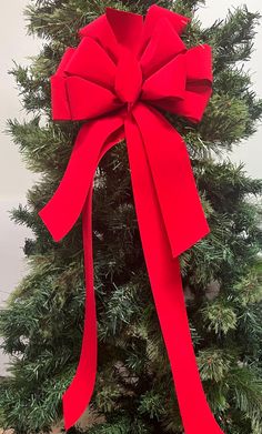 a large red bow on top of a christmas tree