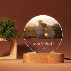 a personalized photo is displayed on a wooden stand next to a potted plant