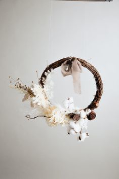 a wreath with cotton and pine cones hanging from it's side on a wall