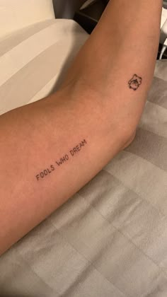 a person laying in bed with a tattoo on their arm that reads, fools who dream