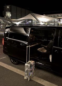 a black van with its door open and luggage in the passenger seat next to it