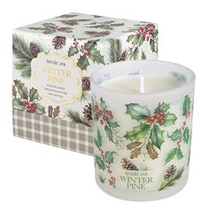 a white candle with holly and pine cones on it in front of a boxed box