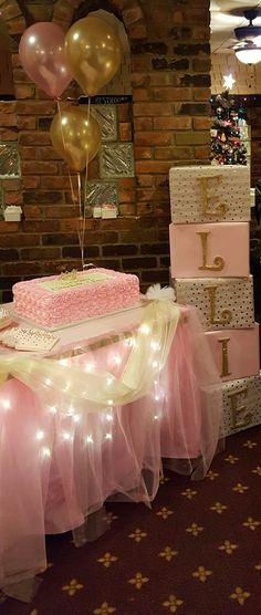 a table topped with lots of pink and gold cake next to balloons in the air