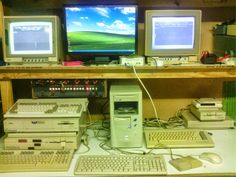 three computer monitors sitting on top of a desk next to two keyboards and mouses