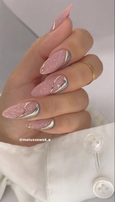 a woman's hand with pink and gold nail polishes on her nails, while she