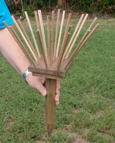 a person is holding a wooden rake in their hand and it's out on the grass