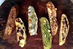 five different types of breads on a wooden platter with nuts and other ingredients