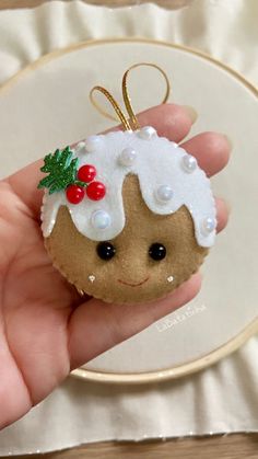 a hand holding a small christmas ornament in it's left hand on a white plate