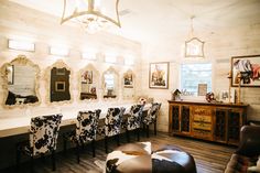 a dining room table with chairs and pictures on the wall above it, along with an ottoman