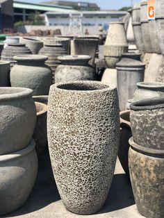 several large vases are lined up on the ground