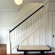 an empty room with a bench under the stairs