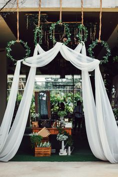 an outdoor ceremony with white drapes and greenery