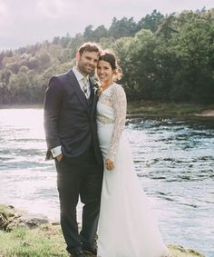 a bride and groom standing next to the water