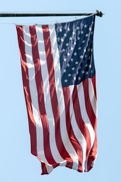 an american flag flying in the wind on a clear day with blue sky behind it