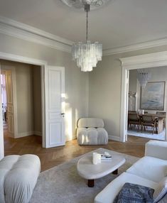 a living room filled with furniture and a chandelier hanging over the top of it