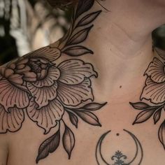 a woman's back with flowers and a crescent tattoo on her chest, in black ink