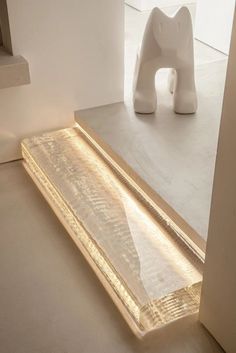 an elephant sculpture sitting on top of a floor next to a white wall and window