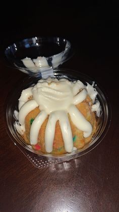 a cupcake with icing on it sitting in a glass dish