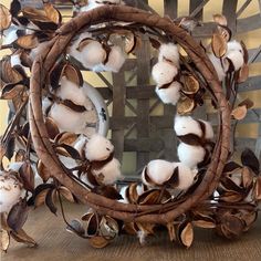 a wreath made out of branches with cotton balls and leaves on the front, sitting on a table