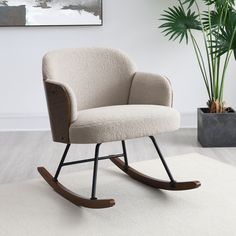 a rocking chair sitting on top of a white rug next to a potted plant