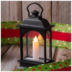 a lit candle sitting on top of a wooden table next to a christmas gift wrapper