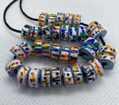 multicolored glass beads with black cord on white table top, ready to be used as bracelets or necklace