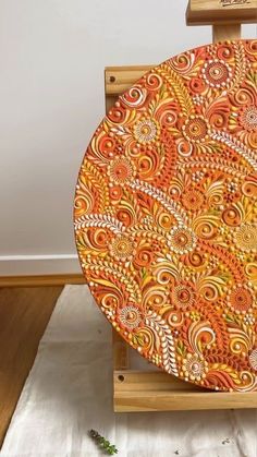 an orange and yellow plate sitting on top of a wooden easel in front of a white wall