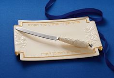 a knife sitting on top of a plate with a blue ribbon around the edge that says,