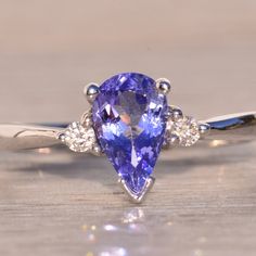 a tan and white gold ring with an oval cut tanzanite surrounded by diamonds