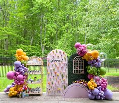 an outdoor display with balloons and flowers in the shape of a birdcage, surrounded by greenery