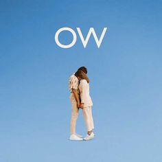 two people standing in front of the word ow on a blue sky with white letters