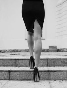 a woman in high heels walking up some steps with her skirt pulled back to the side